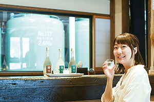 店舗の一角「酒蔵BARえん」で飲みくらべセットを楽しむ真野さん。3種のセットは平日限定で1,840円。カウンターのガラス越しには貯蔵タンクが見える
