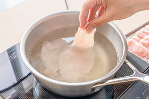 （2）鍋に湯を沸かし、すりおろししょうがを入れる。火を弱めてから豚肉を少量ずつ入れ、色が変わったら取り出して水気を切る