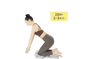2つのクッションを半分に折り畳み、1つは膝、もう1つは足の下に敷いて膝立ち。体の前で腕を伸ばして、1ℓのペットボトルを両手で持つ