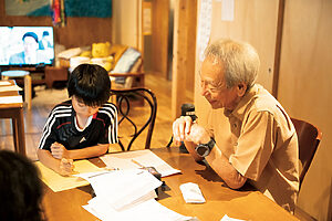 利用者に夏休みの宿題を教わる小学生。「このくらいの問題が頭のいい刺激になりますね」、と男性