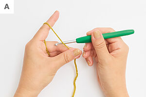 糸端から10cmほどの位置を左手の親指と中指で押さえ、かぎ針を糸の向こう側に当てる