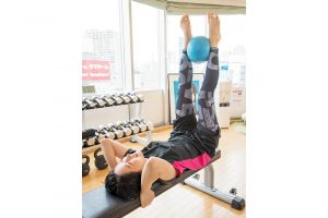 2.仰向けの状態で、ボールを脚で挟んだまま上げ下げするレッグレイズ。下腹部の引き締めに効果的。「久々だからきっつい!　いつもは楽勝なのに……」。