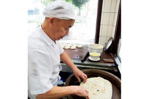 一枚ずつ餅を焼き上げる名物的な職人さん。「店先で出来上がるまでの手順を見られるのが楽しいです」